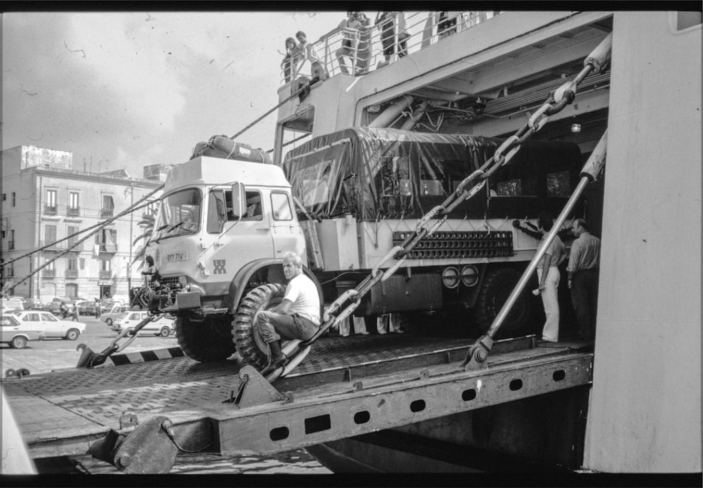 truck-driving-onto-a-ships-ramp-in-a-busy-port-o6arif6vyu8